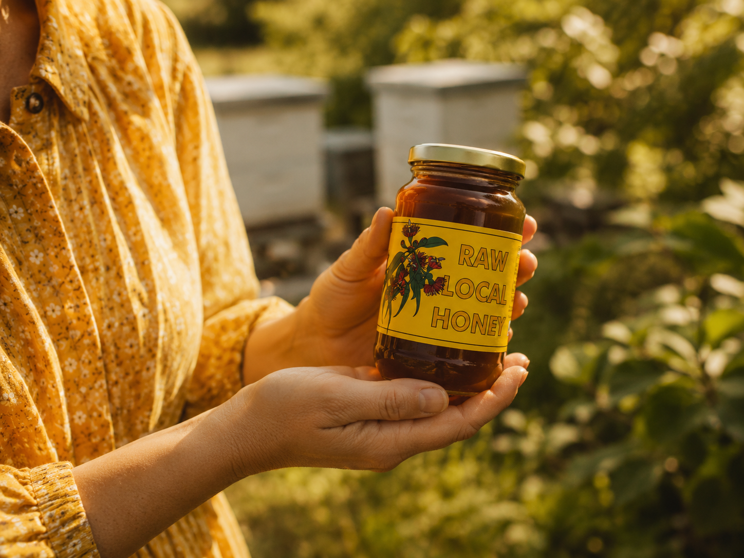 Holding a jar of Edmonds raw local honey in the apiary